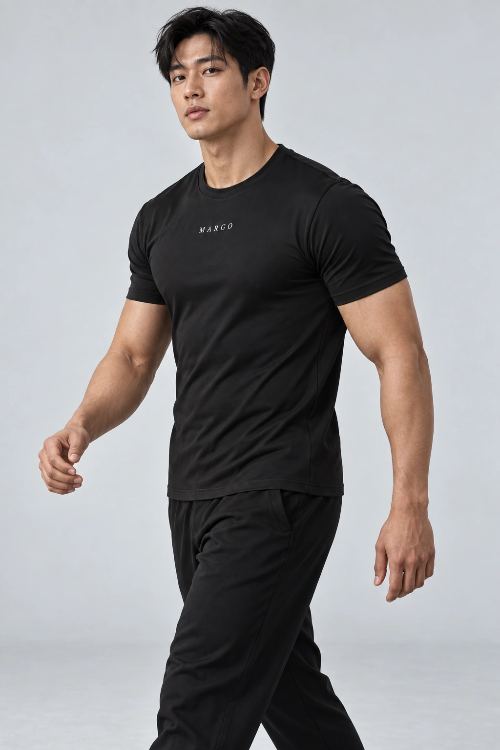 MARGO Performance Tee, worn by a man with black hair stepping forward in a gray studio